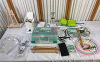 Overview photo showing various crafting supplies including two wooden easels, storage box, embroidery hoops, metal stands, small containers, and plastic bags with accessories.