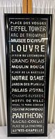 Full view of the framed poster showing list of famous French landmarks in white and gold text on black background, with a glossy black frame.