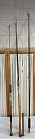 Four fishing poles standing vertically showing varying lengths and handle styles.