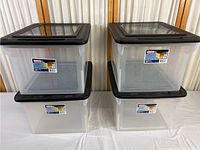 Four Sterilite plastic file boxes stacked in two columns of two each with black lids. Boxes are clear plastic with front labels.