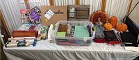 Wide shot of all Thanksgiving craft supplies and decorations arranged on a table including pumpkins, turkey centerpiece, wall organizer, trimmer, and assorted craft items