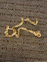 Tangled 14k gold bracelet displayed on fabric background, showing chain detail and clasp.