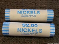 Two rolls of nickels, each wrapped in white and blue paper rolls indicating $2 worth of nickels each from N.F. String & Son, Inc.