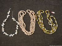 All three beaded necklaces displayed flat on dark background showing overall length and bead colors.