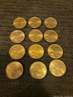 23 US presidential $1 coins arranged in grid pattern on gray surface