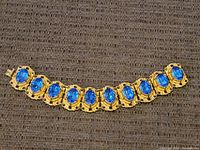 Full view of the vintage costume bracelet showing all blue cabochon stones linked by gold-tone metal.