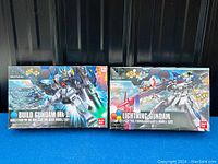 Two unopened Bandai Gundam model kits in 1/44 scale, Build Gundam Mk-II and Lightning Gundam, shown in boxes with detailed cover art.