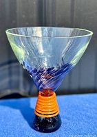 Front view of the hand blown art glass vase showing clear flared rim with blue swirl and orange striped base.