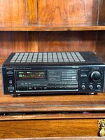 Full front view of Onkyo TX-SV313PRO stereo receiver showing control buttons, tuning display, and large volume knob on wooden shelf.