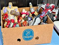 Box of assorted Transformers, Star Wars, and other robot action figures from the 1980s to early 2000s, showing multiple figures including Thanos and a large Transformer with red and grey colors.