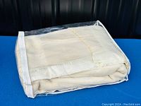 Folded cream white wool blanket with satin edge inside protective zippered bag