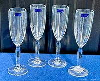 Four Waterford Marquis Omega crystal flute glasses standing upright with blue Marquis labels visible on each glass.