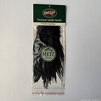 Front view of packaged black dyed saddle hackle from Umpqua Feather Merchants labeled #2 Saddle Dyed Black with Metz Feathers seal.