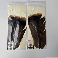 Two sealed packages of Ozark turkey tail feathers, each with brown to cinnamon tip coloration, labeled as Hook & Hackle Canada.