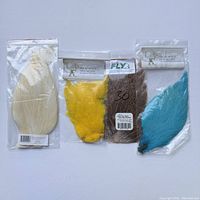 Five packs of assorted fly fishing hen neck feathers in sealed plastic bags on a white background