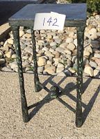 Front view of square cast iron side table on concrete with rock background