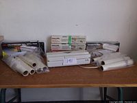 Wide shot showing white vacuum sealer, multiple vacuum bag rolls, and boxed Philips and Toasties replacement bags on a wooden table.