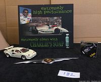 Display of white Lamborghini Countach model car, smaller Formula 1 model car in packaging, Chrysler name plate, and high performance poster