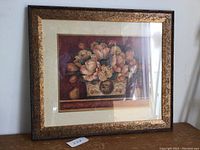 Framed floral print showing peach tulips in decorative vase with bronze textured frame, photo taken from a slight angle.