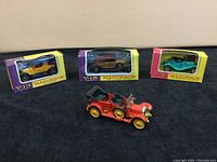 Four vintage Matchbox cars including boxed Y-13 (yellow), Y-14 (teal), Y-15 (black), and loose red 1910 Daimler 38 model.