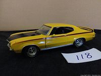 Front and side view of the yellow and black 1970 Buick GSX Tennessee model car on black surface with visible details including rims, decals, and side mirrors.