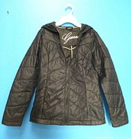 Front view of the black quilted ladies' ski jacket by Guess showing fitted design, zipper closure and hood.