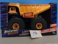 Front view of yellow dump truck in box showing 'Steel Body' label and large black wheels.