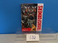 Front view of new Transformers Grimlock action figure in original packaging, showing figure and branding.