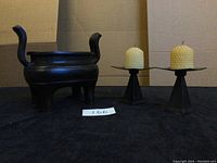 Front view of cast iron planter and two candle stands with candles