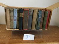 Front view of 10 hardcover vintage books in an open box, titles visible on spine, showing wear