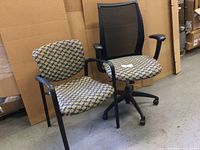 Photo of two chairs: one side chair with patterned upholstery and black metal frame, and one swivel office chair with mesh back and patterned seat.