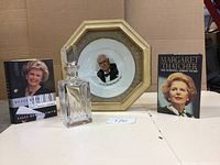 Wide shot showing all lot items including framed Churchill plate, whiskey decanter, and two books.