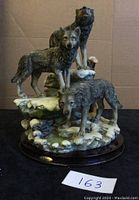 Front view of three wolves resin sculpture showing detailed textures of fur and snowy rocky base.