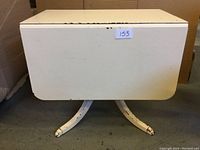 Front view of painted Duncan Phyfe table with one leaf drop down and showing base/claw feet.