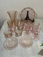 Overview of all 17 pieces of assorted pink depression glass displayed on a white tabletop