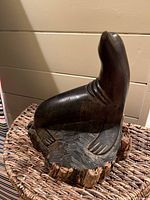 Front view of carved sea lion sculpture showing smooth, dark hardwood with natural wood grain.