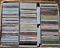 Top down photo showing many CD jewel cases stacked tightly in a cardboard box, visible artists include Billy Joel, Journey, Dierks Bentley, Cherish Bentley, Velvet Revolver, Green R.E.M., Def Leppard