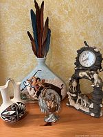 Overall lot showing stoneware vase with feathers, pewter 'War Cry' statue, small native wedding vase, and wolf clock