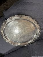 Full view of large oval silver-plated serving platter showing overall ornate design and etched center floral pattern.