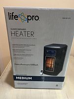 Photo of the Life Pro electric quartz heater in original box showing brand, model, and key features such as heating area up to 1200 sq. ft., 3 wrapped quartz infrared elements, built-in safety shutoff, and inclusion of remote control.