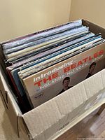 Box with vintage vinyl records showing The Beatles 'Introducing: The Beatles' record on top