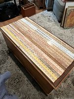 Overhead view of 14 wooden yardsticks laid out on table showing various advertising and measurement markings.