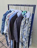 Six men's Tommy Bahama shirts of various colors and patterns on hangers showing overall lot contents.