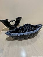 Three-piece set showing the bowl foreground and wedding vase to the left with flower frog to the right all in black and blue drip glaze