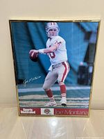 Full view of framed Joe Montana poster showing him preparing to throw a football, in San Francisco 49ers uniform, with a clear view of Sports Illustrated and Joe Montana text at bottom.