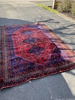 Full view of vintage larger area rug showing red and blue geometric design with star and floral motifs.