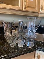 Photo showing assortment of pitcher, decanters, ice buckets, and cocktail glasses on kitchen counter