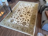 Full view of wool carpet with visible floral and vine design on cream and green background in living room setting