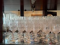 Crystal stemware arranged on a glass shelf including wine glasses and champagne flutes with detailed cut pattern design, showing clarity and uniform style.