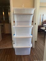 Five clear plastic storage bins stacked, showing full set of lids and bin sizes